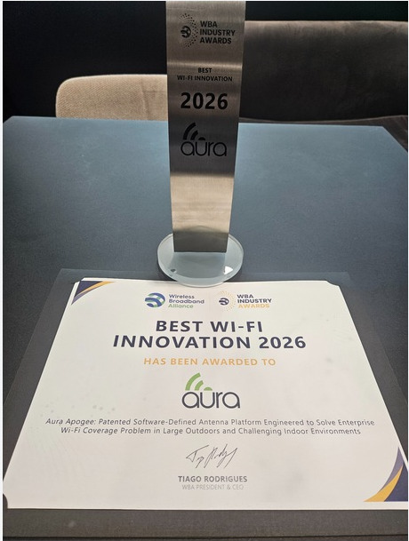 WBA Industry Awards 2026 trophy engraved Best Wi-Fi Innovation 2026 with the Aura logo, beside the certificate awarded to Aura for Apogee: Patented Software-Defined Antenna Platform Engineered to Solve Enterprise Wi-Fi Coverage Problem in Large Outdoors and Challenging Indoor Environments. Signed Tiago Rodrigues, WBA President and CEO.